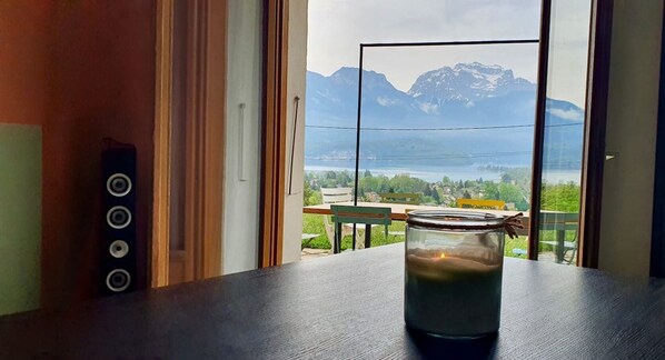 A candle on a table by a window with a mountain view.