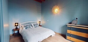A bedroom with a bed, two bedside lamps, a dresser, and a wall-mounted light fixture.
