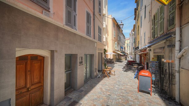 A narrow cobblestone street with buildings on either side, outdoor seating, and a Coca-Cola vending machine. - Charmant 2 Pieces Proche Forville A1b269 (Cannes)