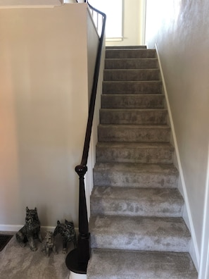 Una escalera alfombrada con barandilla y rellano decorado con figuritas de perros.