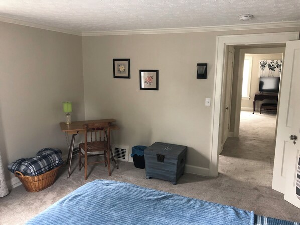 Un dormitorio con cama, escritorio, silla, lámpara y cómoda.