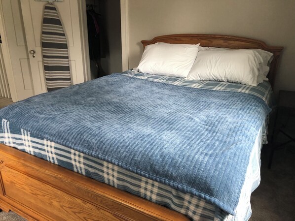 A bed with a blue and white checkered bedspread, a wooden headboard, and white pillows.