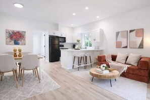 Une cuisine moderne avec des meubles blancs, un réfrigérateur noir et un îlot central doté de tabourets.
