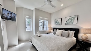 Ein modernes Schlafzimmer mit einem großen Bett, einem Deckenventilator und Kunstwerken an den Wänden.