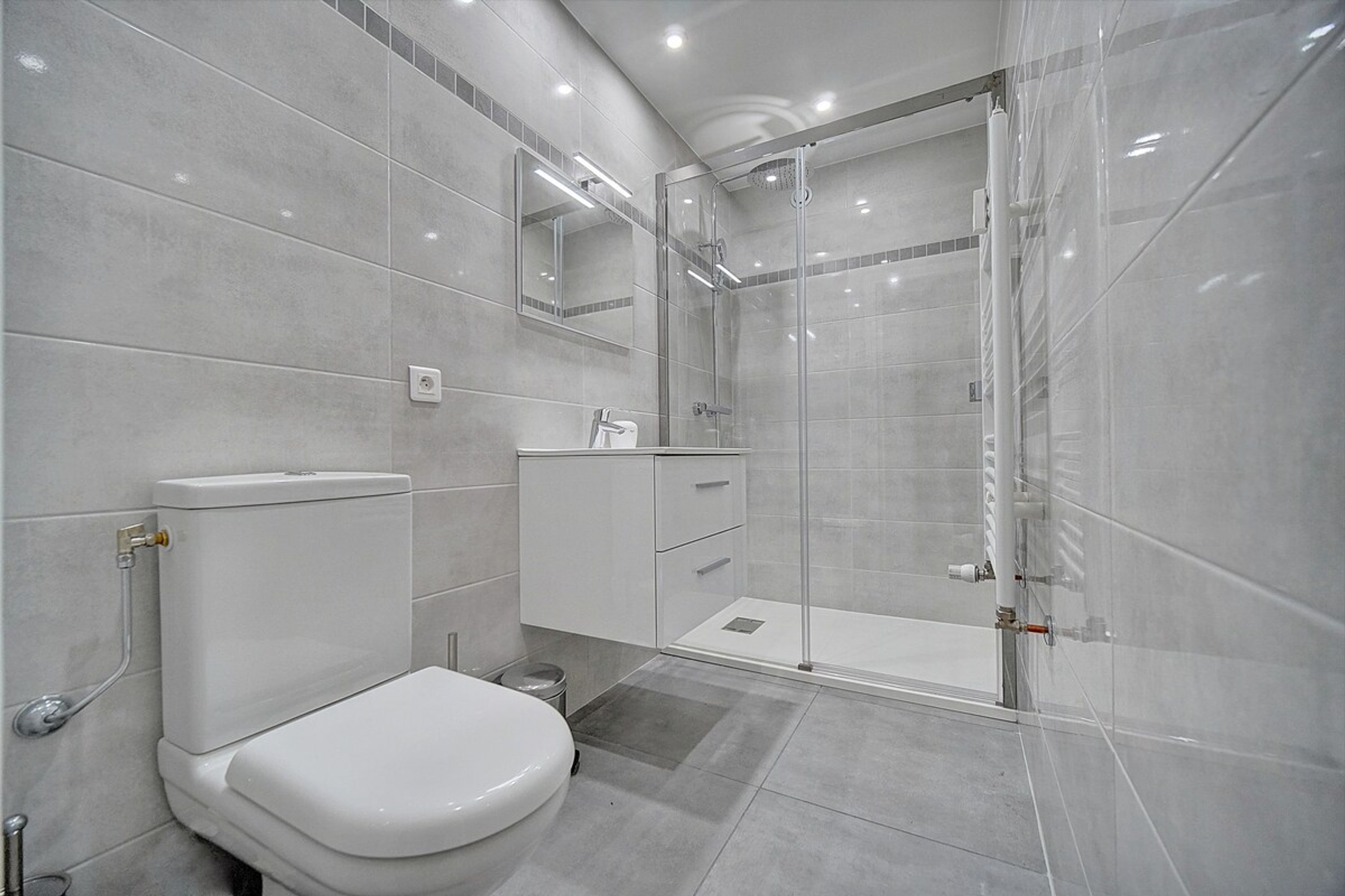 Un bagno moderno con toilette, lavandino e cabina doccia in vetro.