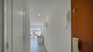 A hallway with a wooden door, a white wall-mounted phone, and a view of a balcony with a table and chairs. - Studio Moderne ET Renove A 2MN Croisette A0b166 (Cannes)