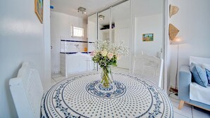 Een eetruimte met een ronde tafel, een bloevas en een witte stoel.