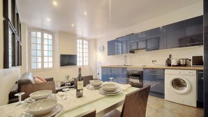 Una cocina moderna con armarios oscuros, horno empotrado y lavadora.
