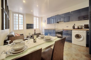 Una cocina moderna con armarios oscuros, horno empotrado y lavadora.