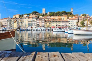 A waterfront marina with boats docked, a wooden pier, and a row of colorful buildings in the background. - Joli 4 Pieces Proche Vieux Port A3b075 (Cannes)