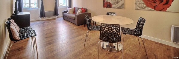 A dining area with a round table and chairs, a sofa, and a TV in the background. - 2 Chambres 2 SDB Meydanier-forville A2b105 (Cannes)