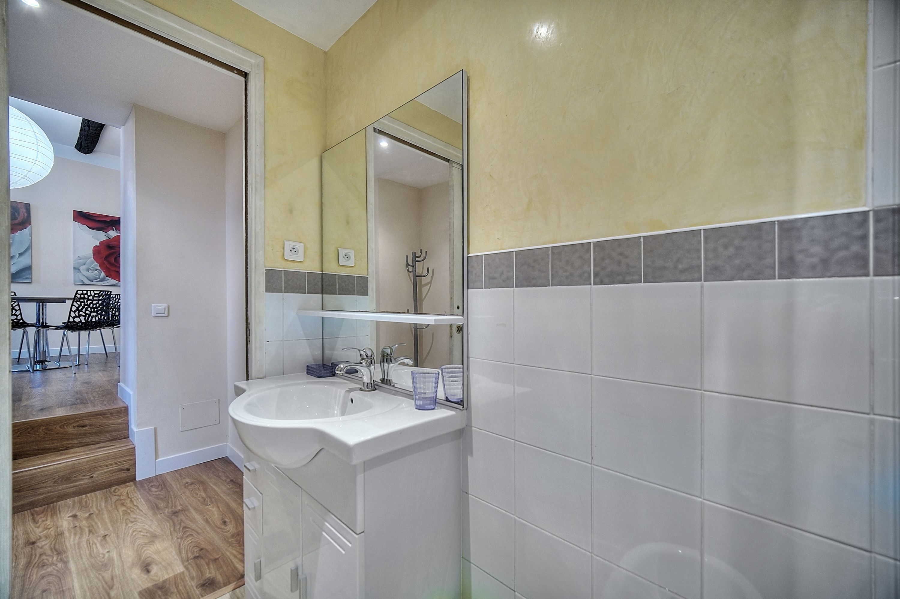 A bathroom with a white sink, mirror, and tiled walls.