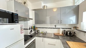 Een kleine keuken met een magnetron, broodrooster, spoelbak en een klein oven.