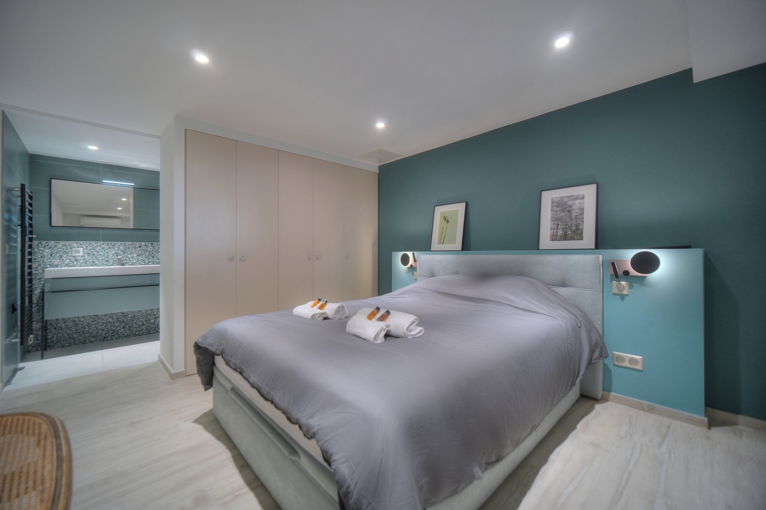 Une chambre moderne avec un grand lit, une armoire intégrée et une salle de bain équipée d’une douche et d’un lavabo.