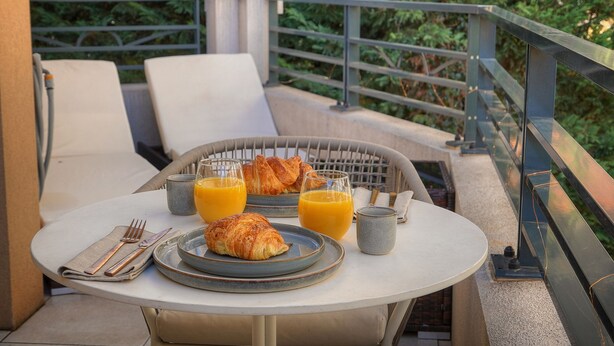 A breakfast setup on a balcony with a table, chairs, croissants, and orange juice glasses. - Superbe Studio Terrasse Parking A0b200 (Cannes)