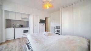 Een moderne hotelkamer met een groot bed, een kitchenette en een plafondlamp.