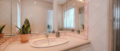 A bathroom with a large mirror, a sink, and a potted plant.