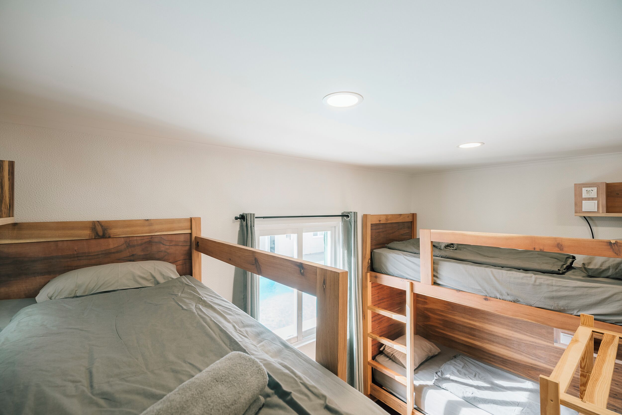 A room with two bunk beds, a window with curtains, and a ceiling light.