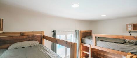 A room with two bunk beds, a window with curtains, and a ceiling light.
