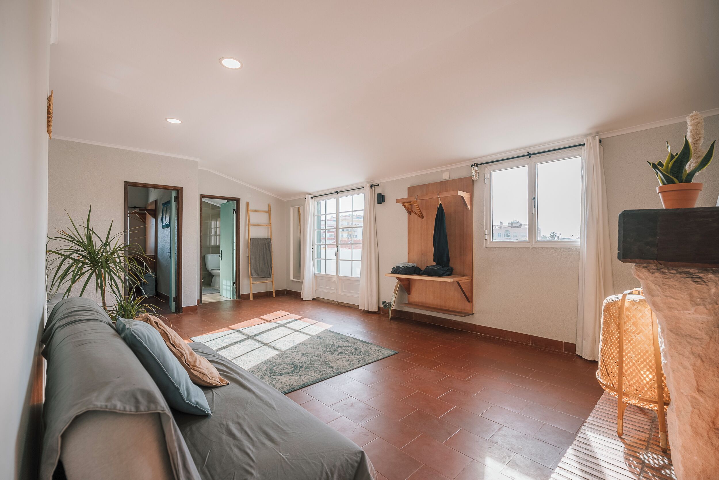 A spacious living room with a sofa, a wooden bench, and a large window.