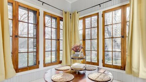 A room with large windows, a round table with woven placemats, and a decorative vase. - Cozy North End Farmhouse  Easily Walk Downtown (Boise)