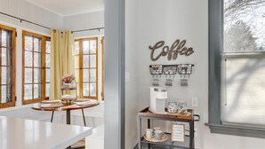 A modern kitchen with a coffee station, wooden windows, and a wall-mounted coffee sign. - Cozy North End Farmhouse  Easily Walk Downtown (Boise)
