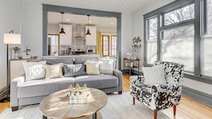 A modern living room with a grey sofa, a patterned armchair, and a coffee table. - Cozy North End Farmhouse  Easily Walk Downtown (Boise)
