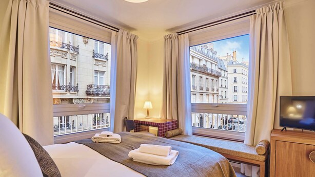 A hotel room with a large bed, a desk with a lamp, and a TV. - Sublim AC Apartment 3 Bdr Saint Germain des Prés (Paris)