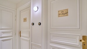 A set of white doors with nameplates and a round light fixture above them. - Sublim AC Apartment 3 Bdr Saint Germain des Prés (Paris)