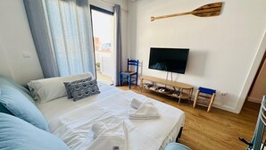Ett hotellrum med en säng, en tv, en träspade på väggen och utsikt över omgivningarna.