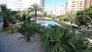 Ett bostadsområde med en swimmingpool omgiven av palmer och grönskande växter.