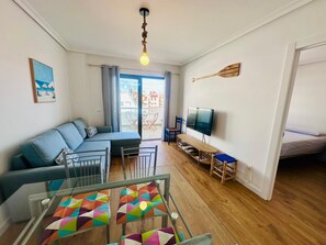A living room with a sofa, a TV, a wooden floor, and a balcony with a view. - A1145 - Wonderful beach apartment with swimming pool (Villajoyosa)