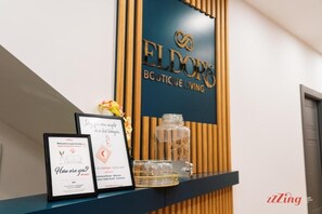 Ein Empfangsschalter mit einem Schild, auf dem 'Eldor's Boutique Living' steht, und gerahmten Willkommenskarten.