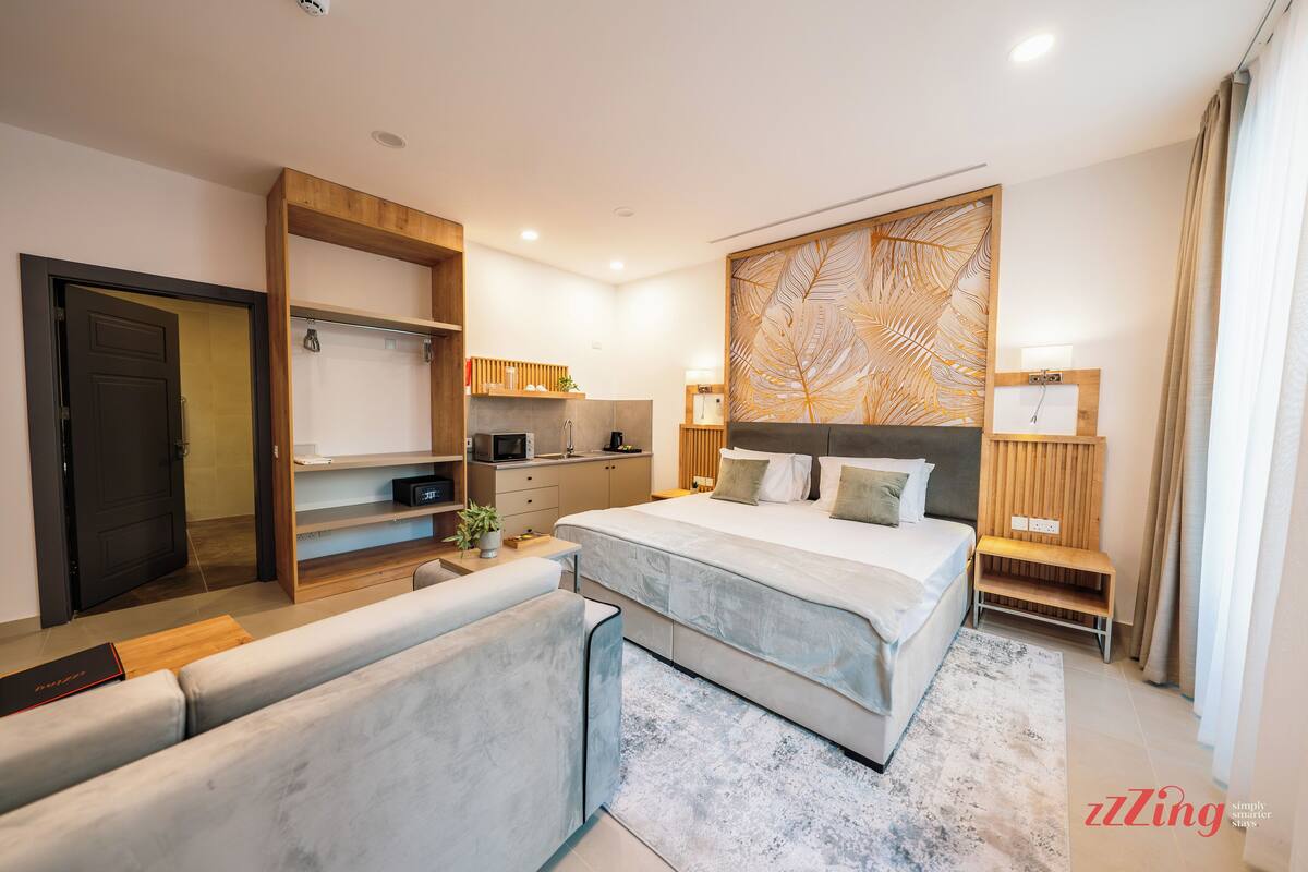 Une chambre moderne dotée d’un grand lit, d’une armoire intégrée, d’un coin salon et d’un bureau.