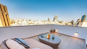 A rooftop terrace with a wicker sofa, a round table with a drink, and potted plants. - El Doris Boutique Living St Julians  (St. Julian's)
