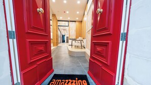 A red door leading into a hotel lobby with a sofa and a table. - El Doris Boutique Living St Julians  (St. Julian's)