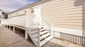 Un bâtiment d’un seul étage, à l’extérieur blanc, avec une porte d’entrée et un petit porche doté d’une balustrade blanche.