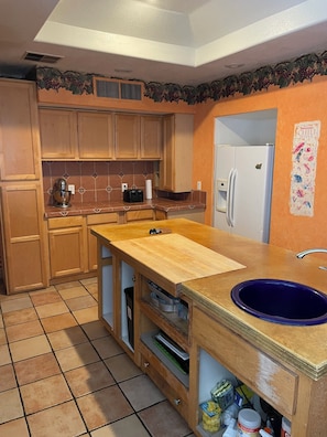 Una cocina con armarios de madera, encimera de mármol, un lavabo y un refrigerador.