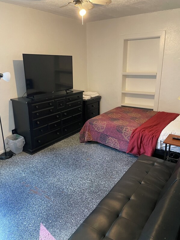 Une chambre à coucher avec un lit, une commode, un téléviseur et un ventilateur de plafond.