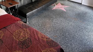 A hotel room with a black leather sofa, a bed with a red blanket, a lamp, and a wall with 'Hollywood' written on it. - DOWNTOWN PHX PRIVATE BEDROOM SHARED BATHROOM KITCHEN COMMON AREAS SWIMMING POOL (Phoenix)