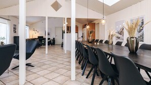A spacious dining area with a long table, black chairs, and a high ceiling with skylights. - 4 Star Holiday Home in Blokhus (Blokhus)