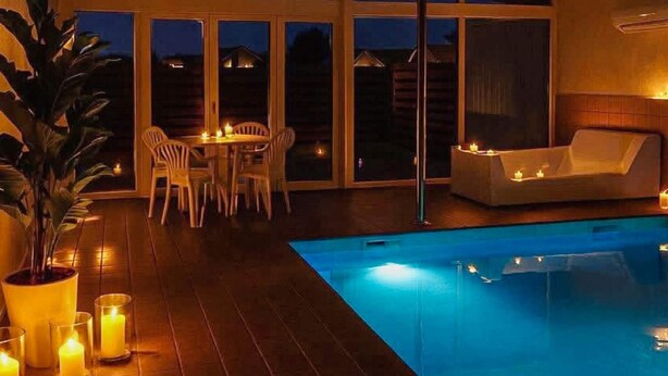 A pool area with a table and chairs, a sofa, and candles. - 4 Star Holiday Home in Blokhus (Blokhus)