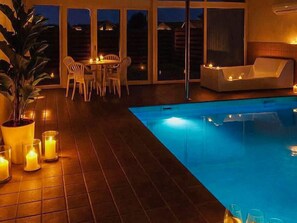 Un espace piscine aménagé avec une table et des chaises, un canapé et des bougies.
