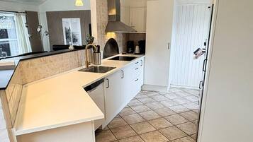 A modern kitchen with a white countertop, stainless steel appliances, and a tiled floor.