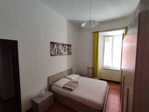 Een slaapkamer met een bed, nachtkastje en een schilderij aan de muur.