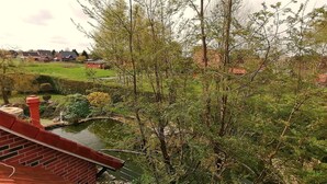 A residential area with a pond, trees, and houses in the background. - Cozy vacation apartment "Lütje Moew", 4-room with roof terrace, rural location (Leezdorf)