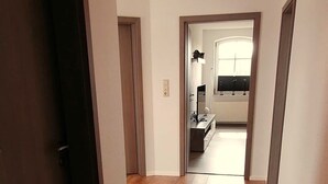 A hallway with wooden flooring leading to a kitchen area. - Cozy vacation apartment "Lütje Moew", 4-room with roof terrace, rural location (Leezdorf)