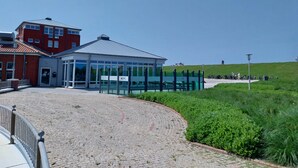 A building with a glass facade and a red brick structure. - Cozy vacation apartment "Lütje Moew", 4-room with roof terrace, rural location (Leezdorf)