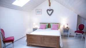Ein Schlafzimmer mit einem hölzernen Bett, zwei Nachttischen, einem Schreibtisch und zwei Stühlen.