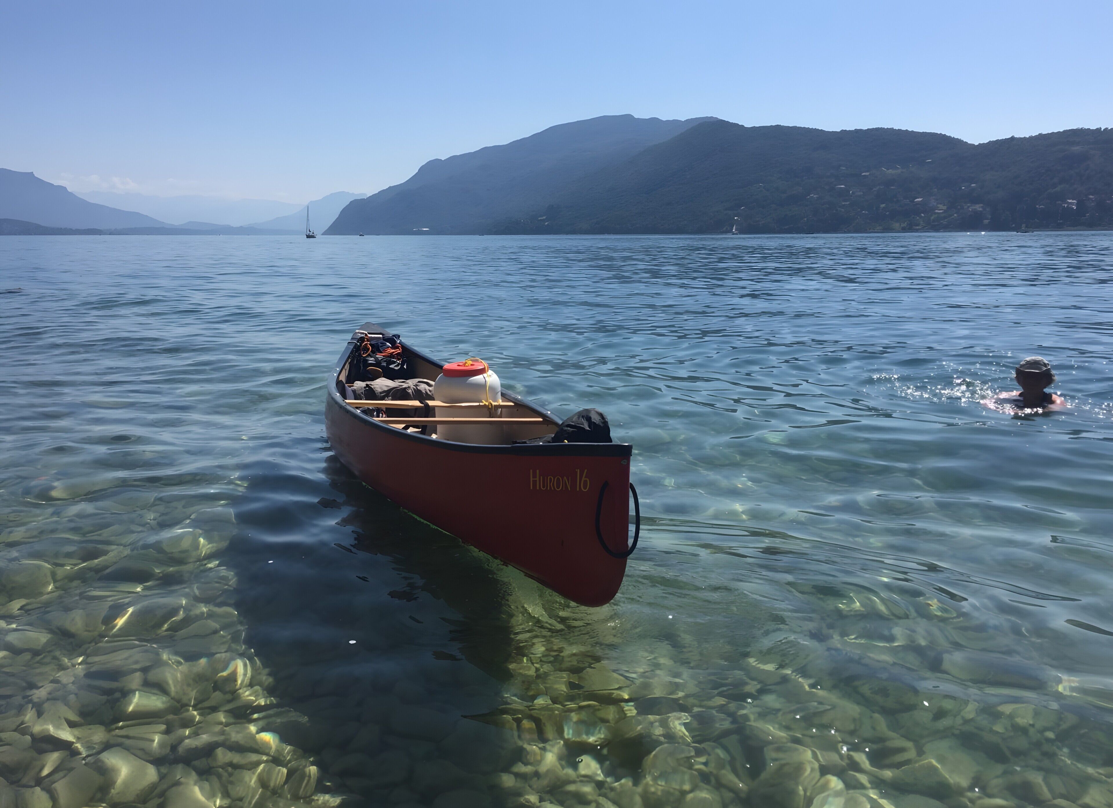 A small boat named 'Huron 16' on clear water with visible rocks at the bottom.